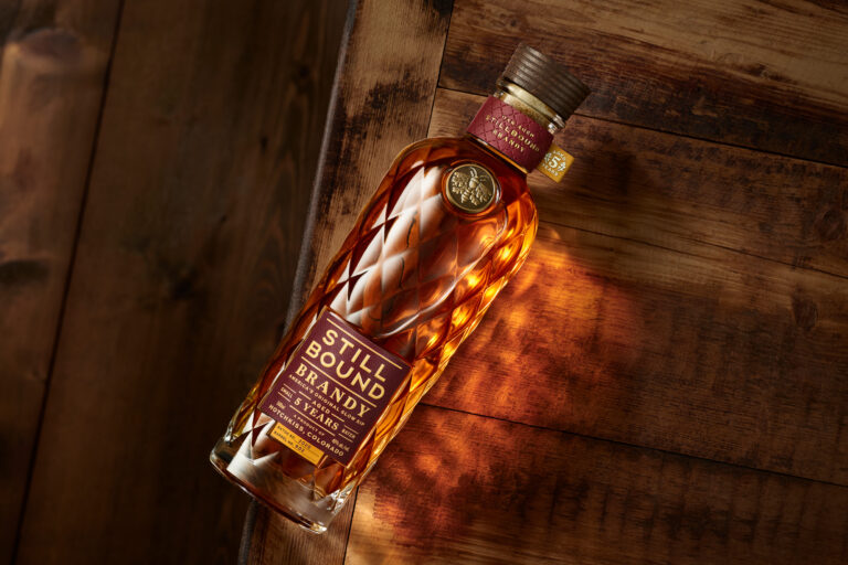 Stillbound premium brandy and pommeau branding and package design featuring a bespoke bottle, custom closure, oak moth emblem, and quilted glass inspired by mountain heritage and outdoor ritual.